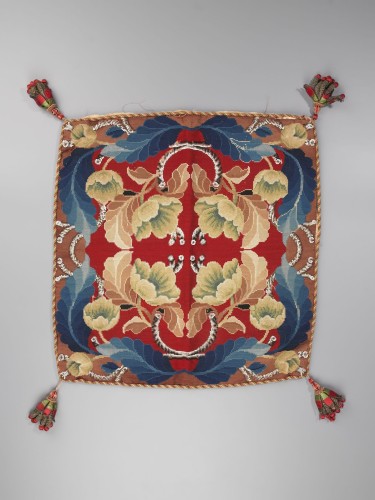 Kussen, bovenzijde met wol op stramien geborduurd, tapisserie, floraal symmetrisch patroon, kwasten op de hoeken